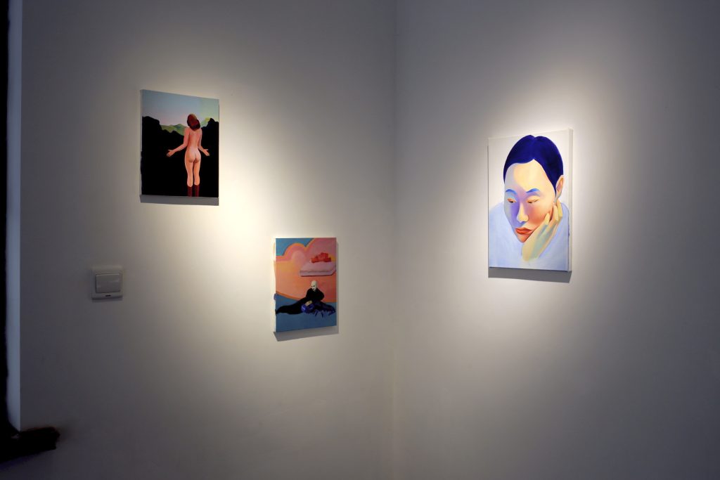 A wall with 3 paintings. A female nude on the left, a man lying on the ground to its right. And a female self portrait looking into nowhere on the very right.