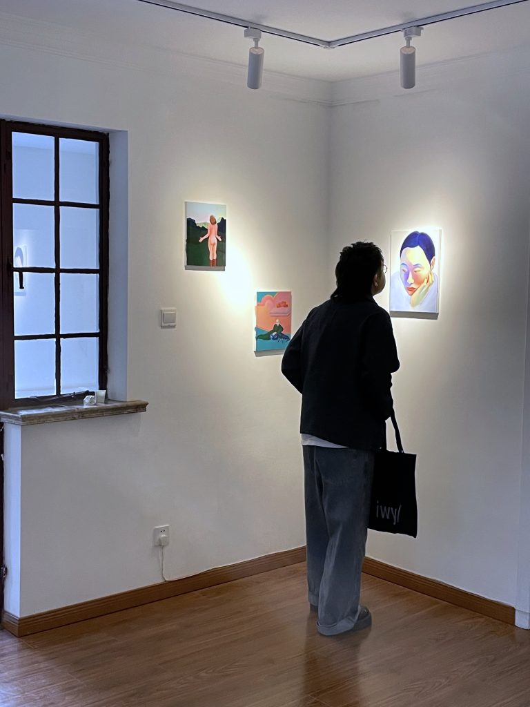 A man is looking at a group of paintings hanging on the wall
